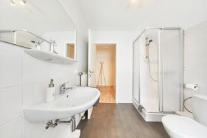 La salle de bains blanche est pourvue d'un lavabo et d'une douche. dans l'établissement Wohnung 1- nur 5 min. zum Europapark, à Ettenheim