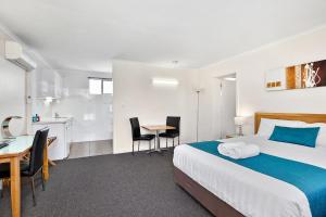 a hotel room with a bed and a table and chairs at Thunderbird Motel Yass in Yass