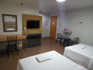 a hotel room with two beds and a desk and a television at Meaco Royal Hotel - Batangas City in Batangas City