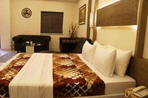 a hotel room with a bed and a chair at Hotel Avalon Suites in Multan