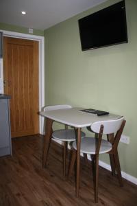 een tafel en stoelen in een kamer met een televisie bij Amberleigh House Annex in Newmarket
