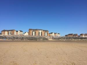 a sandy beach with houses in the background at Beach Break Aberavon Holiday Home by the Sea in Port Talbot