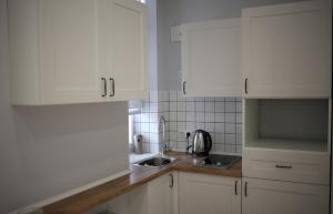 uma cozinha com armários brancos e um lavatório em Del Rey Comfort em Lviv