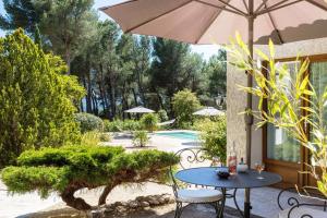 a patio with a table and chairs and an umbrella at Les Mazets du Luberon in Puget