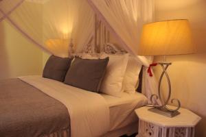a bedroom with a bed and a lamp on a night stand at Le Rustique in Nanyuki