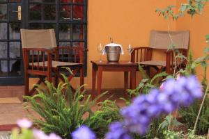 two chairs and a table in a garden with purple flowers at Le Rustique in Nanyuki