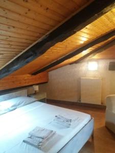 コンメッツァドゥーラにあるMansarda 2 del Capitelの木製の天井の客室のベッド1台分です。