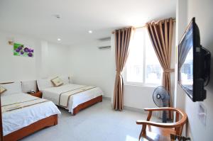 a bedroom with two beds and a tv and a window at Vagibi Hotel in Dong Hoi