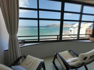 um quarto com duas cadeiras e vista para a praia em Canteras 38 em Las Palmas de Gran Canaria