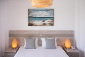 een slaapkamer met een bed met 2 lampen en een schilderij bij Alkinoos Beach Hotel in Gerakini
