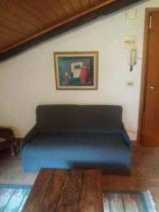 un sofá azul en una sala de estar con una pintura en Maso del Capitel, en Commezzadura