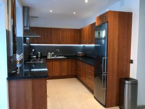 kuchnia z drewnianymi szafkami i lodówką ze stali nierdzewnej w obiekcie Villa with Heated Pool and Jacuzzi close to Puerto Banus and Beach w mieście Estepona