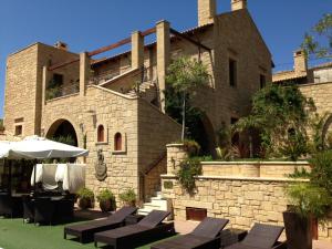 a building with chairs and umbrellas in front of it at Palazzo Loupassi Boutique Villas in Vasilópoulon