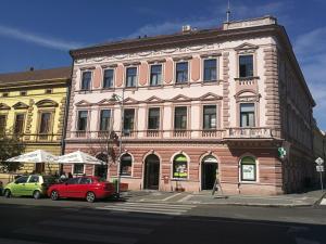 budynek z dwoma samochodami zaparkowanymi przed nim w obiekcie Sunny Aircon Apartment in the Centre of Slaný w mieście Slaný