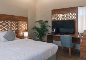 a bedroom with a bed and a desk and a television at فندق جمانة ينبع in Yanbu