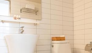a white tiled bathroom with a toilet and a window at Hotel Kyungsung in Busan