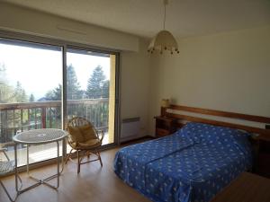 1 dormitorio con cama, mesa y balcón en Les Sorbiers - Grand T4 ensoleillé avec Vue Panoramique, en Font-Romeu-Odeillo-Via