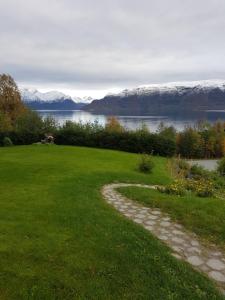 a walkway in a field with a lake and snow covered mountains at Solbakken 27 Apartment in Lyngseidet