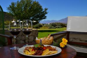Viñas De Cafayate Wine Resort في كفايات: طاولة مع طبق من الطعام وكأسين من النبيذ