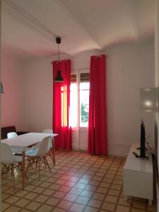 タラゴナにあるcervantes 3の赤いカーテンとテーブル、窓が備わる客室です。