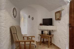 Habitación con 2 sillas y TV en la pared. en Cueva Solano, en Gorafe