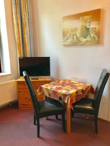 uma sala de jantar com mesa e cadeiras e uma televisão em Pension Holzhausen em Quedlinburg