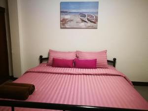 uma cama com lençóis cor-de-rosa e almofadas roxas num quarto em Duangdren Apartment em Chiang Mai