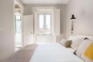 een wit bed in een kamer met een raam bij Charming Apartment Rua da Rosa 33 in Lissabon