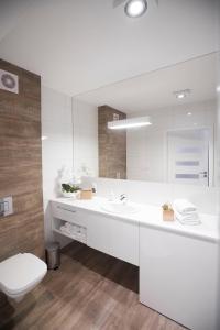 een witte badkamer met een toilet en een wastafel bij Apartament Sedina E306 Park Polanki in Kołobrzeg