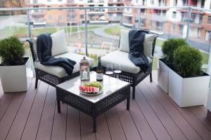 a balcony with two chairs and a table with wine glasses at Apartament Sedina E306 Park Polanki in Kołobrzeg