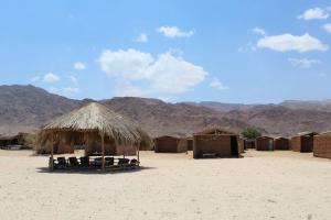 a cluster of huts and chairs in the desert at Aquarium Camp in Nuweiba