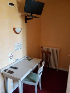 a room with a table and a tv on the wall at Hotel de la Gare in Dol-de-Bretagne