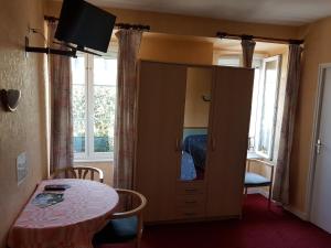 a room with a table and a cabinet with a mirror at Hôtel MAEN-HIR Dol Gare in Dol-de-Bretagne