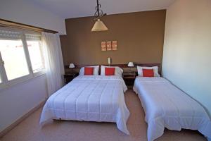 1 dormitorio con 2 camas con sábanas blancas y almohadas rojas en Hotel Santa Eulalia II en Miramar