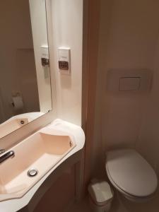a bathroom with a sink and a toilet and a mirror at Hotel de la Gare in Dol-de-Bretagne
