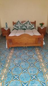 Un dormitorio con una cama de madera sobre una alfombra azul. en Écologie oasis tafilalt CHEZ L' HABITANT, en Er Rachidia 39 fotos más