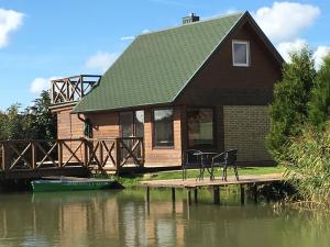 een huis met twee stoelen op een steiger in het water bij Svečių namelis - Pirtis in Vydmantai