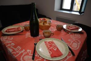 a table with a red table cloth with plates and a bottle at La Victoire in Granville