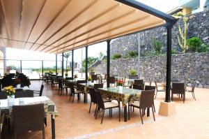 un restaurante con mesas y sillas y una pared de piedra en Luz Del Mar, en Los Silos