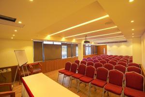 una sala de conferencias con sillas rojas y una pantalla en SAAS Residency en Kozhikode