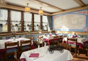 a dining room with tables and chairs and windows at Hotel Presena in Passo del Tonale