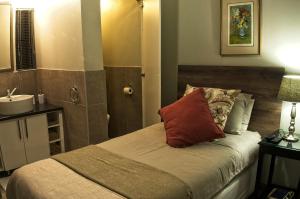 a bedroom with a bed with a sink and a mirror at Rest-a-While Guest House - Pretoria in Pretoria
