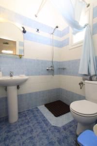 a blue and white bathroom with a toilet and a sink at Smaragda Rooms & Studios in Platis Gialos