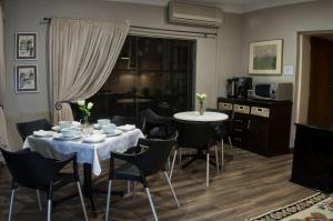 a dining room with a white table and chairs at Rest-a-While Guest House - Pretoria in Pretoria