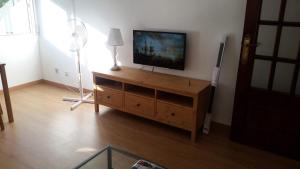 - un salon avec une télévision à écran plat dans un centre de divertissement en bois dans l'établissement Apartamento TISARE wifi, à Valladolid