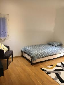 een slaapkamer met een bed en een stoel erin bij Appartement indépendant chez l'habitant in Bezons