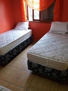 two twin beds in a room with red walls at Apartamento Dois in Caxias do Sul