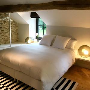 um quarto com uma grande cama branca e janelas em B&B La Gotale em Manhay