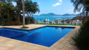 a swimming pool with a view of the ocean at Apartamento em Condominio Fechado - Angra dos Reis - Piscina, Praia, Lazer in Angra dos Reis