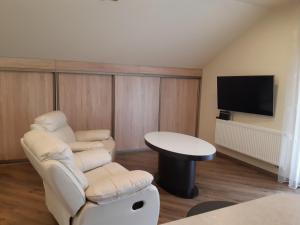 a living room with two chairs and a table and a tv at Zveryno guest house in Vilnius